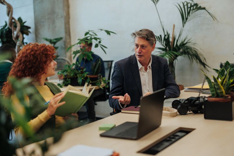 Two managers are discussing business strategy in a modern green office, promoting sustainability and collaboration