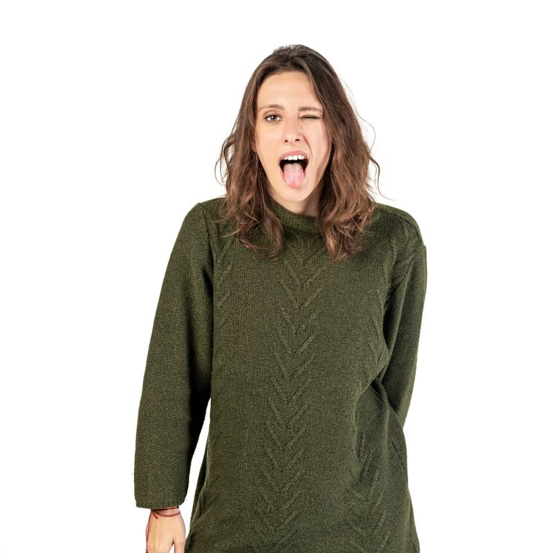 A woman in a green sweater sticks out her tongue playfully against a white background