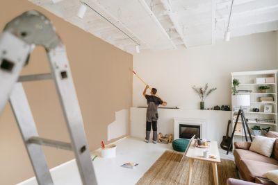 Person painting a wall in a cozy living room.