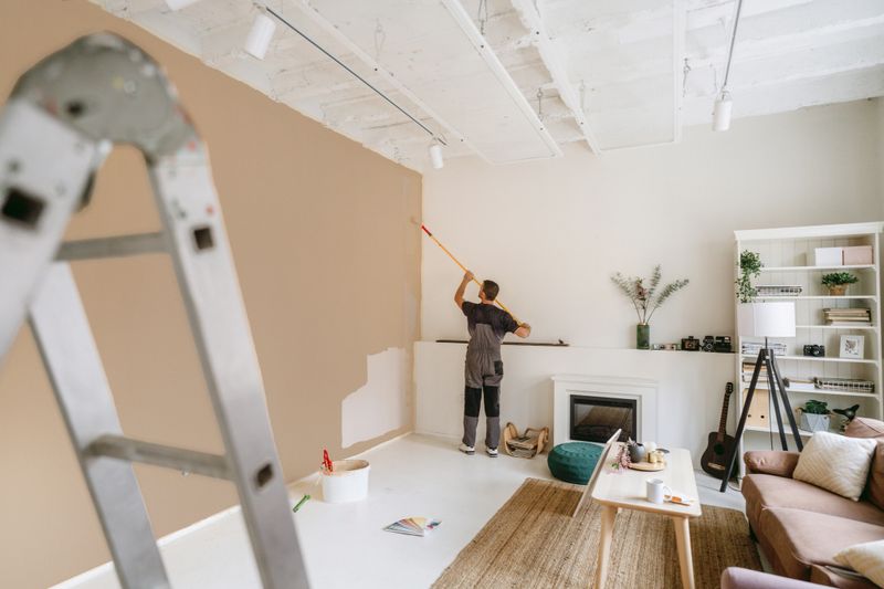 Photo of a professional house painter painting walls in the apartment