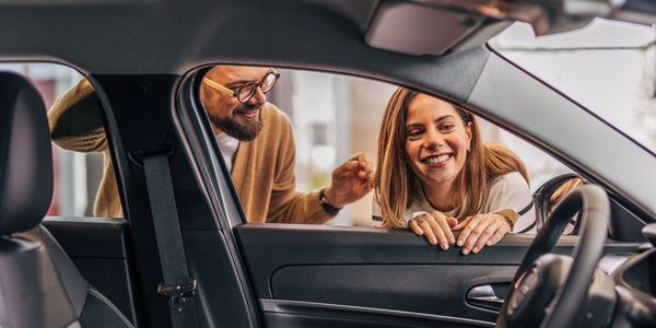 Happy couple smiling and chatting near a car door.
