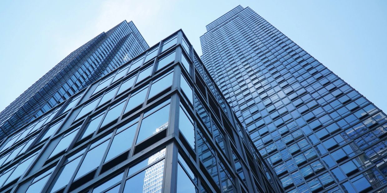 Modern glass skyscrapers reflecting the blue sky from a low angle.