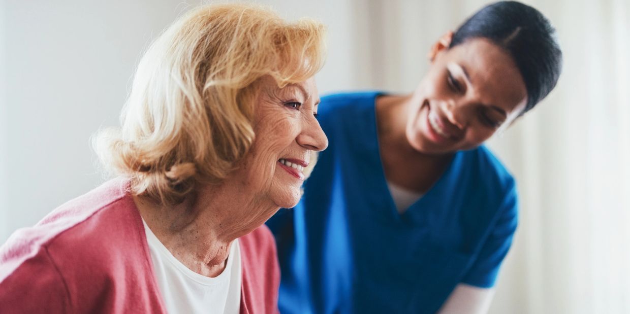 A caregiver warmly supporting an elderly woman.