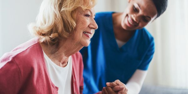A caregiver warmly supporting an elderly woman.