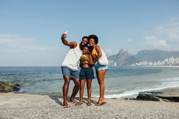 A family taking a selfie at the beach, smiling