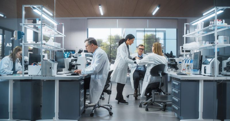 Three Scientists Discussing Latest Bioengineering Discoveries and Sharing Research Data on Vaccine Efficacy. Diverse Male and Female Colleagues Working in a Modern Medical Research Center