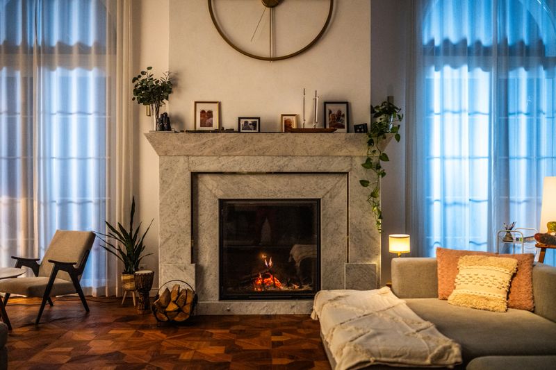 Interior view of a modern living room featuring a stunning marble fireplace, cozy seating, and warm lighting complemented by a beautiful wooden floor and stylish decor elements.