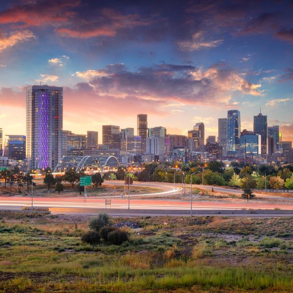 Sunset over a vibrant city skyline with illuminated buildings and busy highways.
