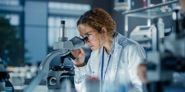 Scientist examining a sample through a microscope.
