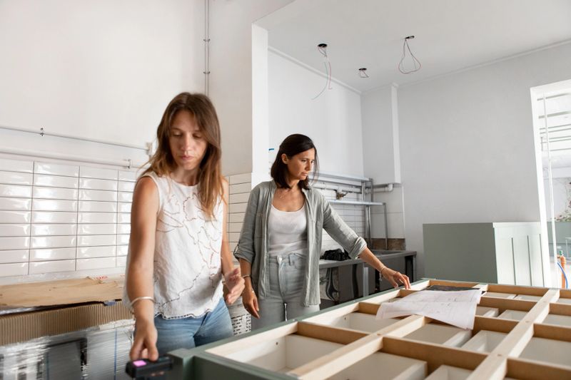 Female architects taking measurements of kitchen furniture and planning kitchen design - Buenos Aires - Argentina
