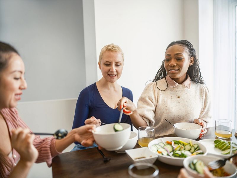 Young Multiracial group of female friends enjoying Vegetable curry dish at the kitchen. They are dressed in casual clothes. Interior of kitchen at private home in Toronto, Canada.