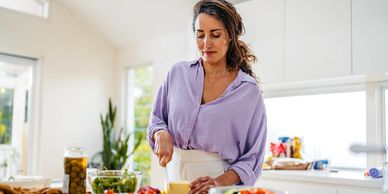 Woman cutting cheese in a bright kitchen preparing a meal.