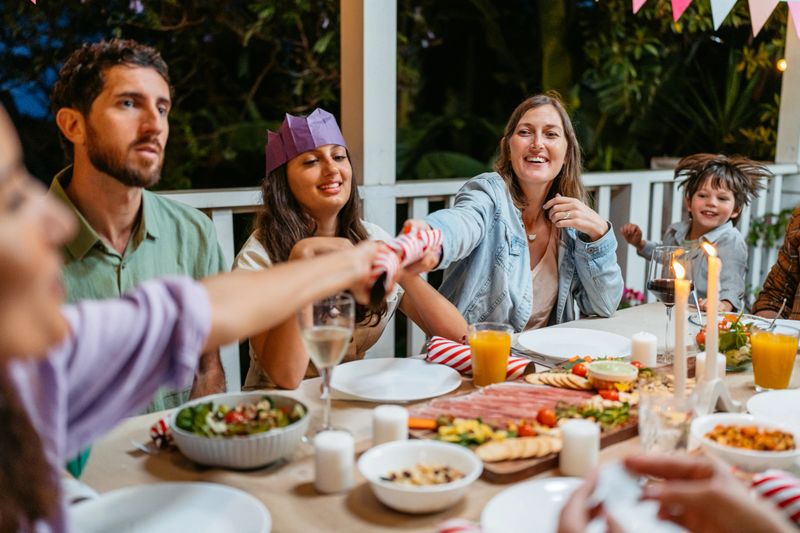 Young family exchanging Christmas crackers during Christmas dinner on the patio outdoors in Sydney in Australia.