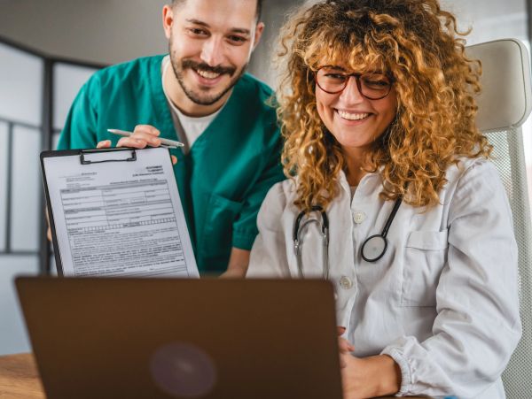 Two doctors smiling, one holding a clipboard.