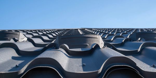 Close-up of black metal roof tiles with a clear blue sky background.