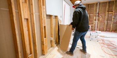 Worker installing drywall in a construction site.