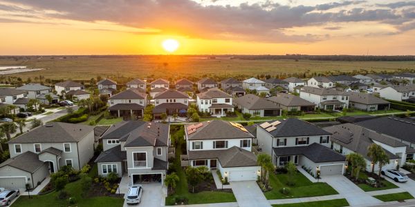 Suburban neighborhood at sunset with rows of houses.