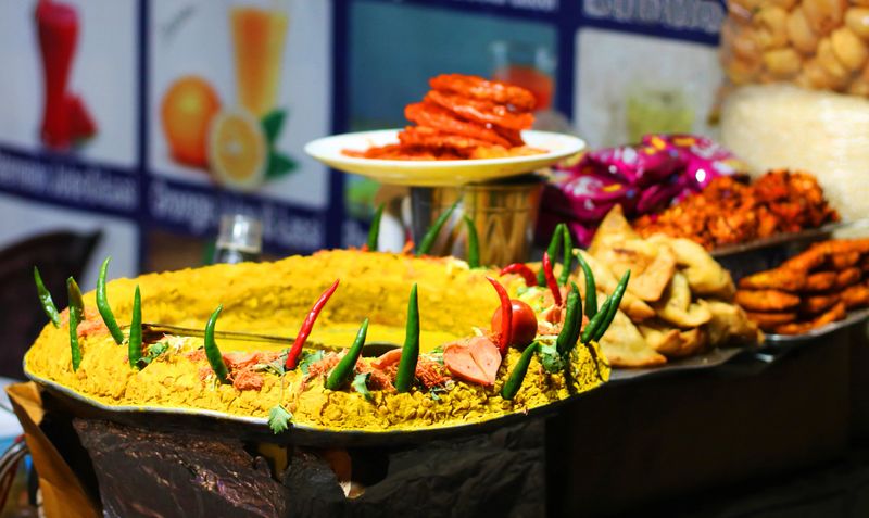 Traditional street food display featuring chaat, a savory Indian snack garnished with vibrant green and red chilies, samosas and pakoras. Perfect for food blogs, menus, and cultural promotions.