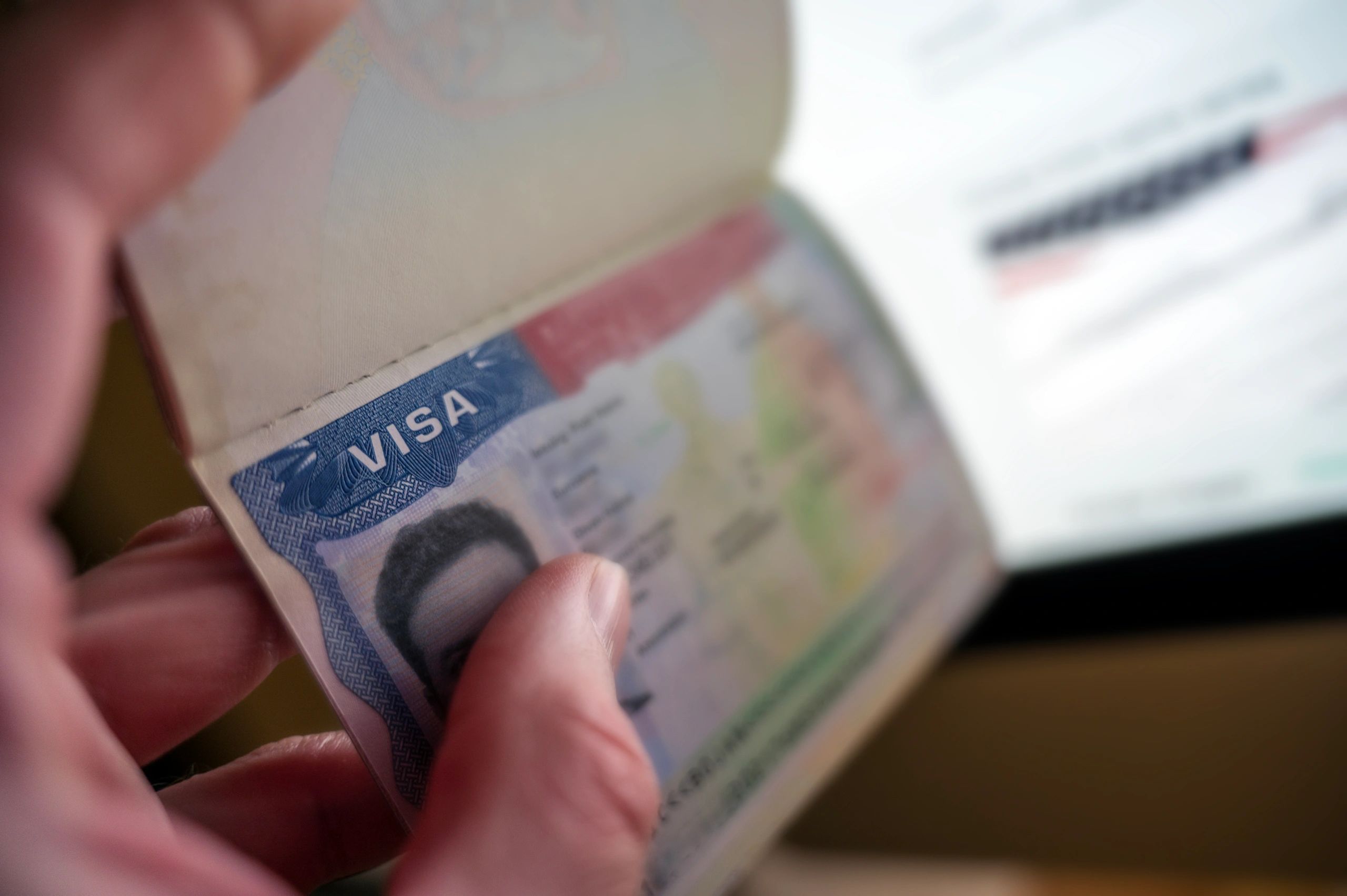 Close-up of a hand holding a visa inside a passport.
