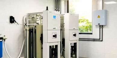 Two large white industrial machines in a clean room with tiled walls and floor.