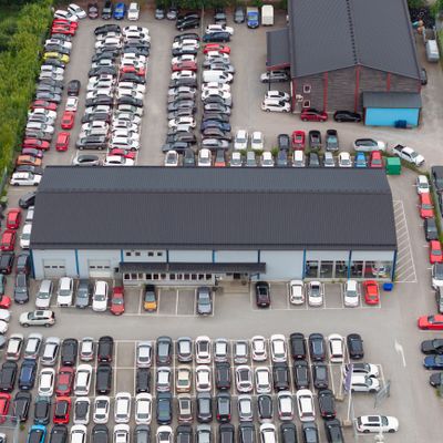 Aerial view of a crowded parking lot with many cars and two large buildings.