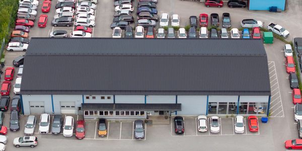 Aerial view of a large parking lot filled with cars around two buildings.