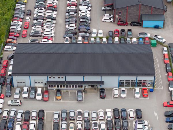 Aerial view of a large parking lot with many cars and two buildings.