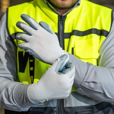 Worker wearing safety gloves and a high-visibility vest preparing for a task.