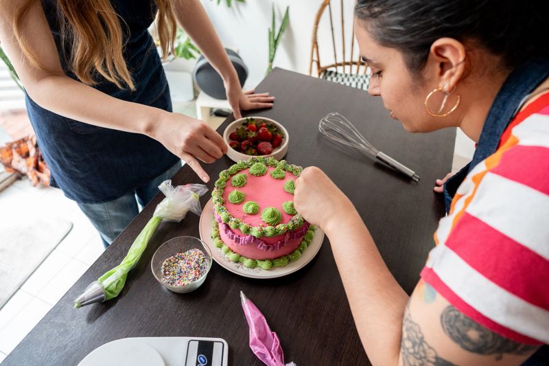Mid adult woman decorating a cake at home