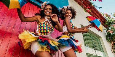 Two women dancing in colorful carnival costumes.