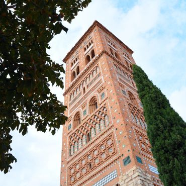Ornate brick tower with detailed patterns against blue sky.