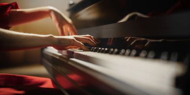 Close-up of hands playing a piano with warm lighting.