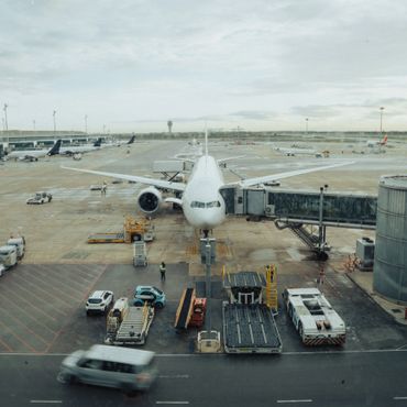 A large airplane docked at an airport gate with service vehicles around it.