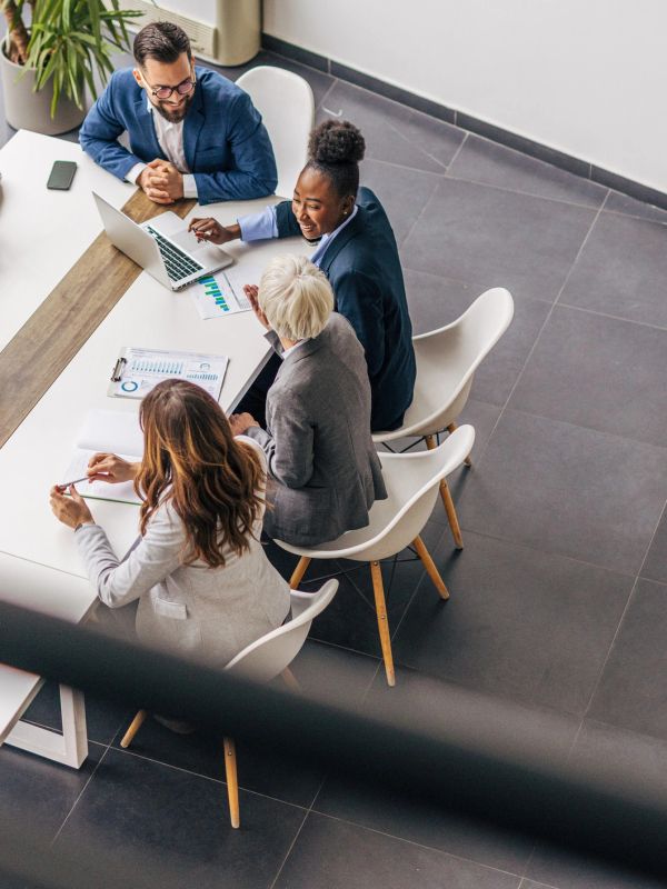 Quatro pessoas discutem negócios ao redor de uma mesa.