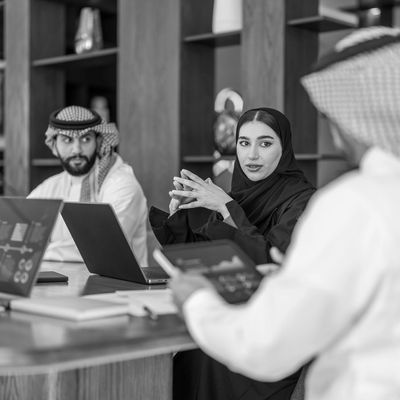 Middle Eastern professionals engaged in a business meeting with laptops and digital devices.