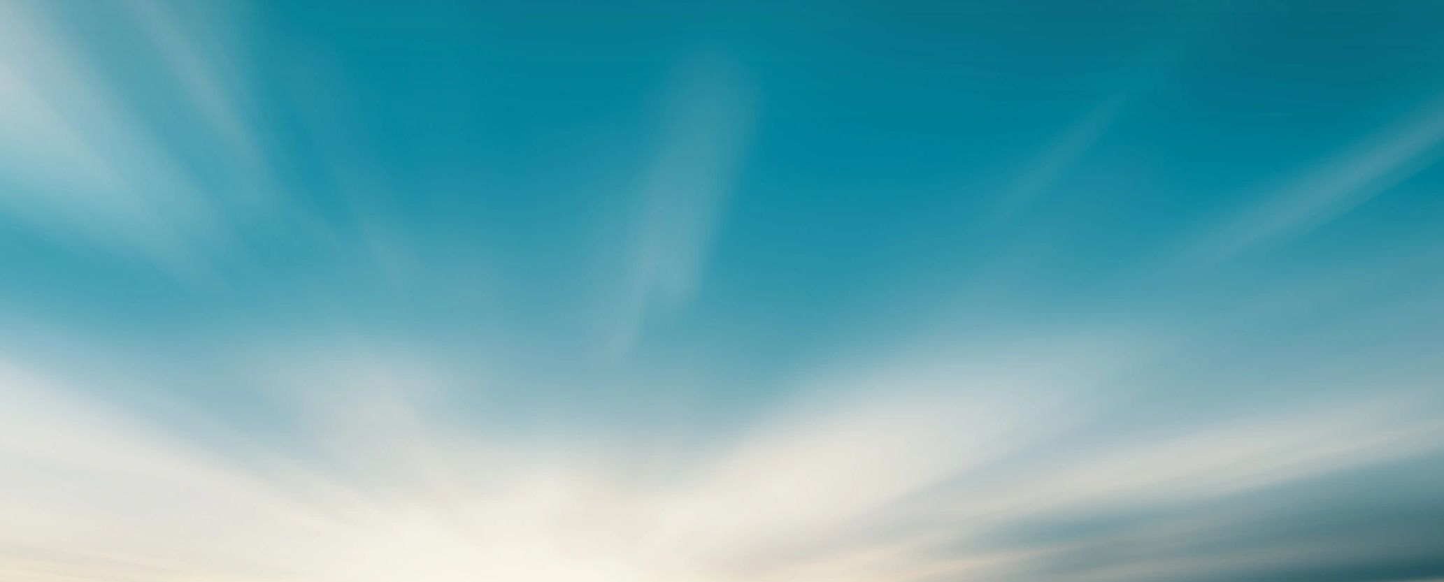 Soft sun rays spreading through a clear blue sky.