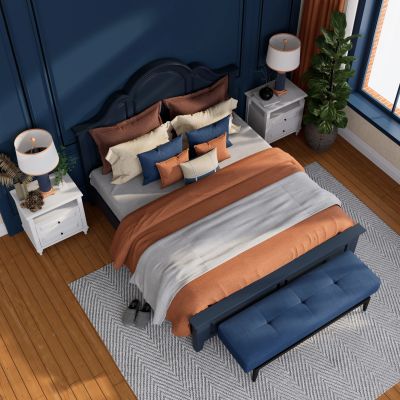 Cozy bedroom with navy and orange bedding, wooden floor, and bedside lamps.