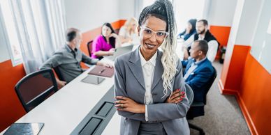 Confident businesswoman standing in front of a meeting with colleagues.