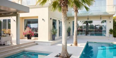 Modern house exterior with a pool and palm trees in the backyard.