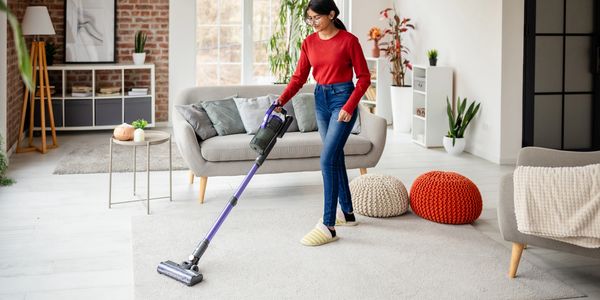 Woman vacuuming a carpet in a modern living room.