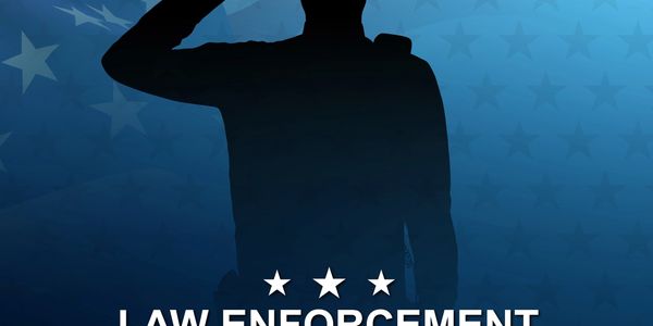 Silhouette of a saluting law enforcement officer with patriotic stars background.