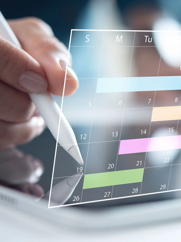 Person using stylus on digital calendar on tablet.