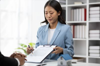 A woman in a blue blazer shows a contract agreement to a client.