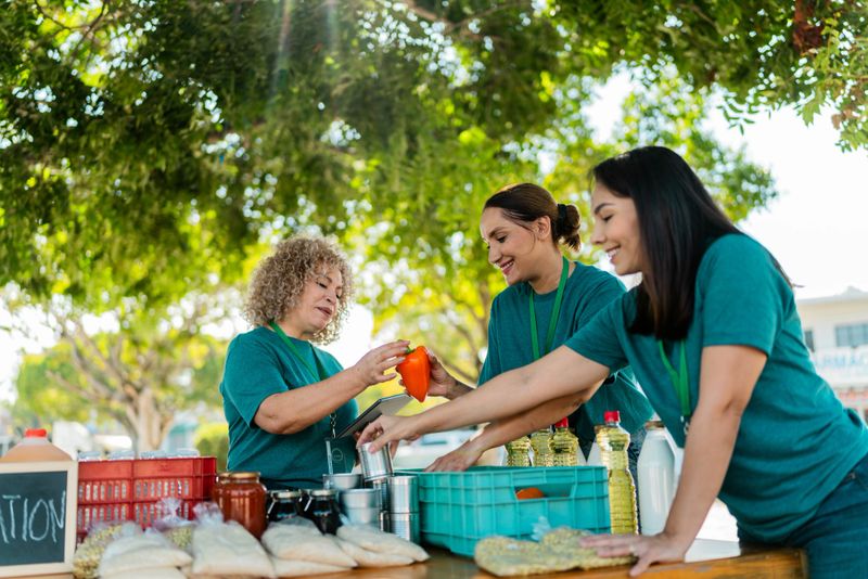 Mature woman talking and organizing donation boxes with volunteers outdoors