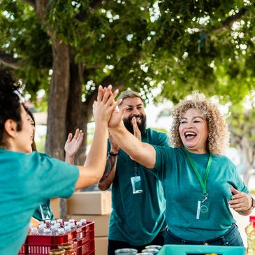 Volunteers happily high-five while working outdoors distributing supplies.
