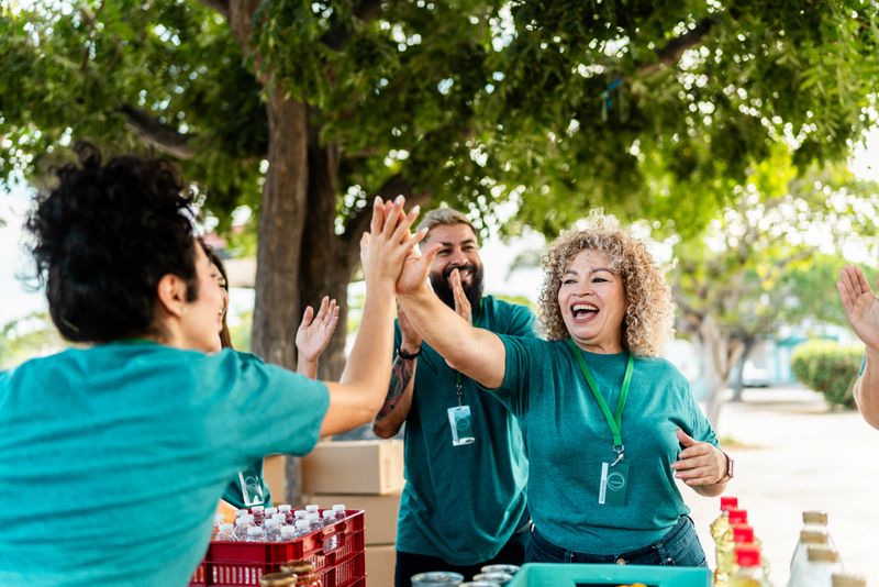 Volunteer organizing donation boxes and doing high-five outdoors