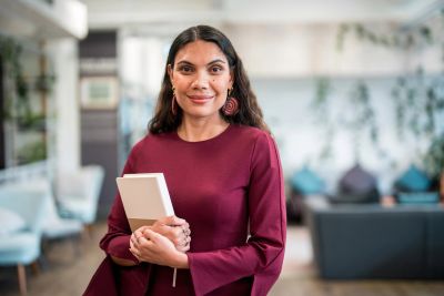 Smiling woman holding a book indoors.