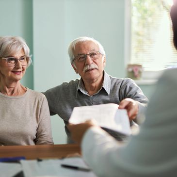 Elderly couple consulting a professional with documents in hand.