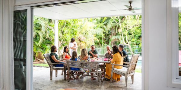 Family gathered outdoors around a table under a covered patio.
