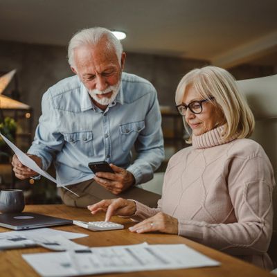 Elderly couple managing finances with documents and calculator at home.